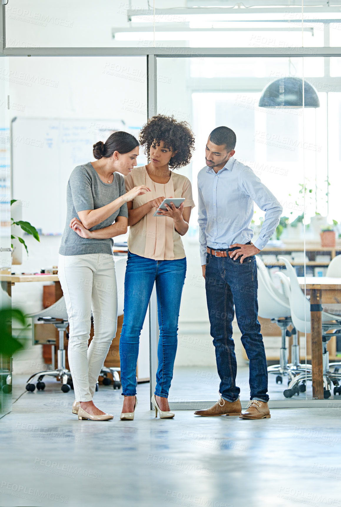 Buy stock photo Shot of a group of office colleagues having a discussion over a digital tablet