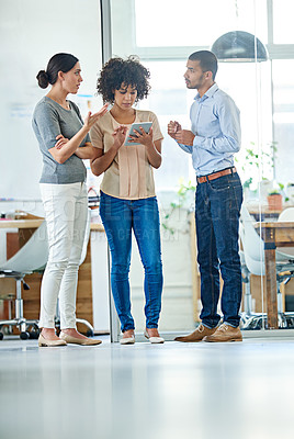 Buy stock photo Shot of a group of office colleagues having a discussion over a digital tablet