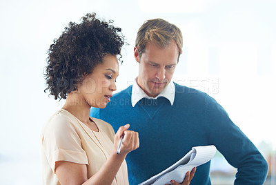Buy stock photo Shot of two business people discussing ideas on a notepad