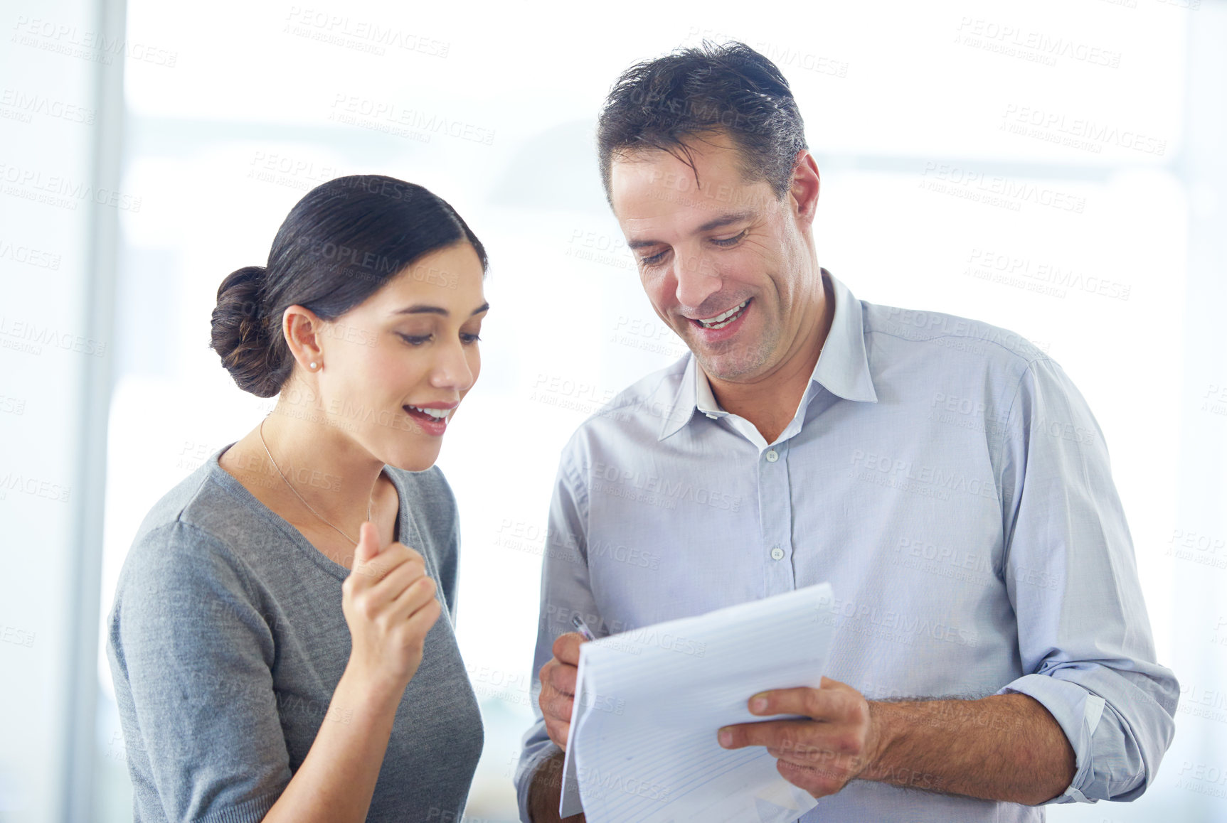 Buy stock photo Shot of two business people discussing ideas on a notepad