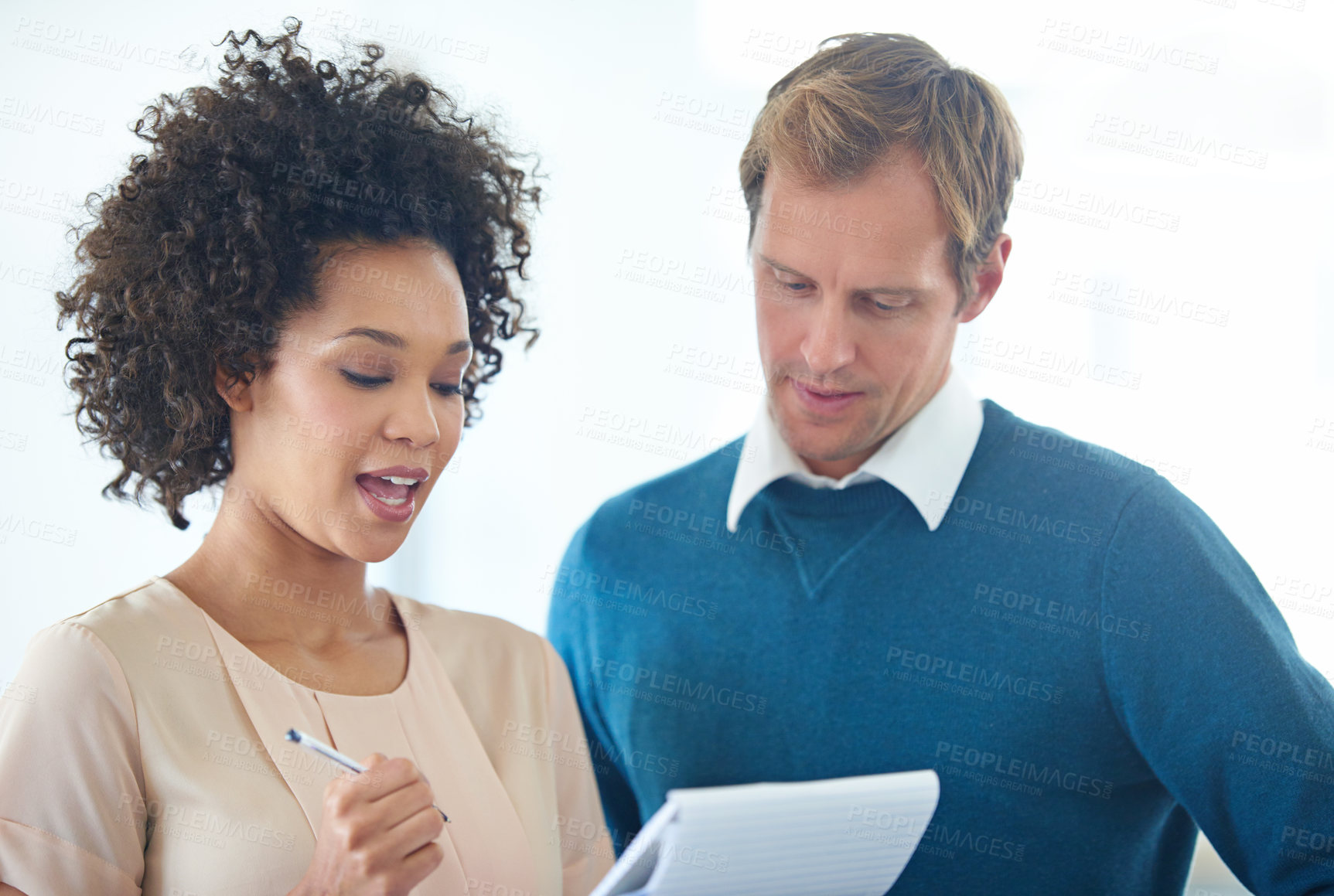 Buy stock photo Shot of two business people discussing ideas on a notepad