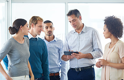 Buy stock photo Shot of a group of colleagues using a digital tablet together
