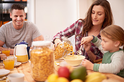 Buy stock photo Mother, girl and breakfast with help for cereal, nutrition and health by table in house. Woman, kid and brunch together in home with dad by kitchen for wellness, eating and assistance with food