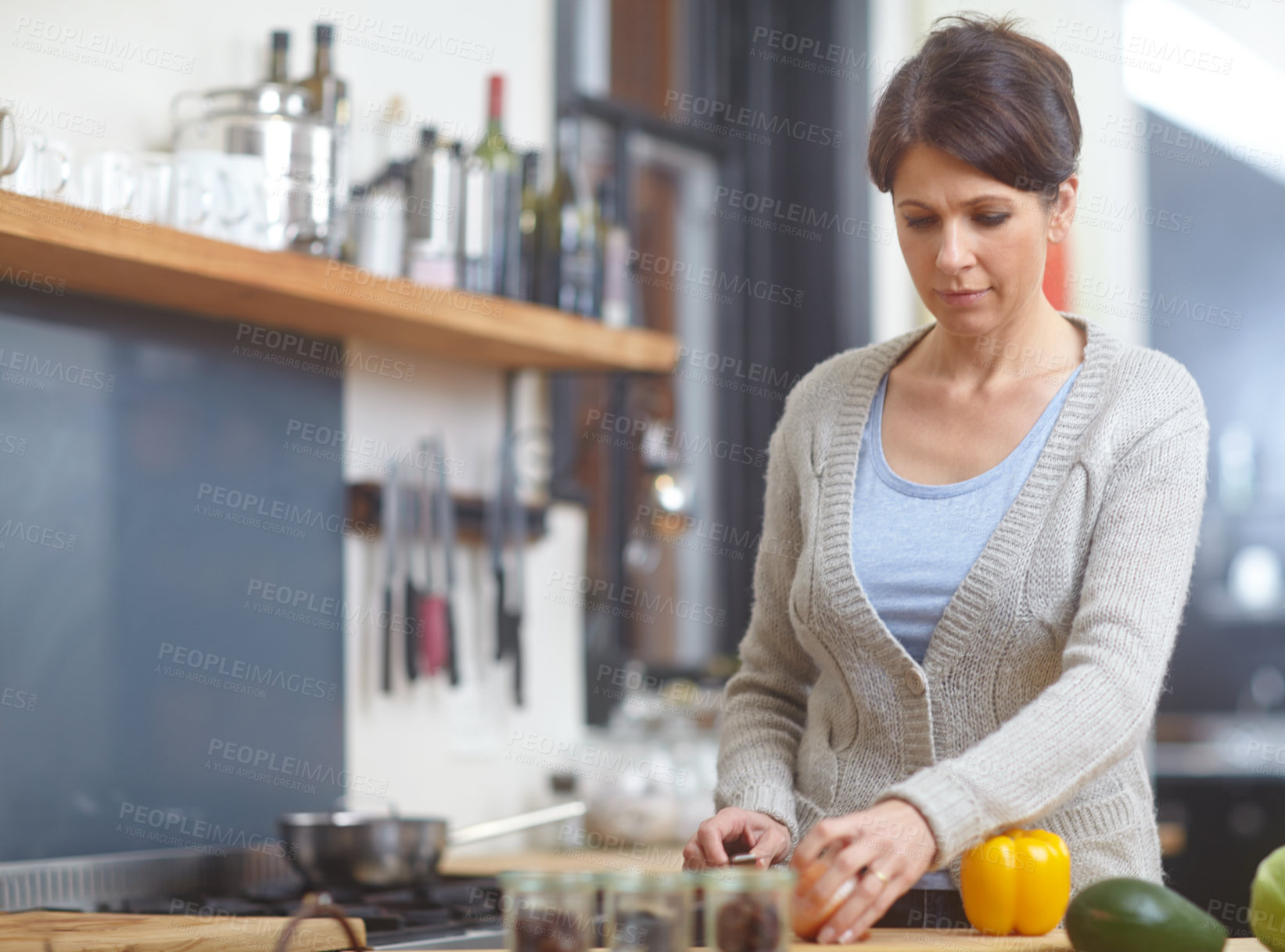 Buy stock photo Shot of an attractive woman chopping vegetables at a kitchen counter