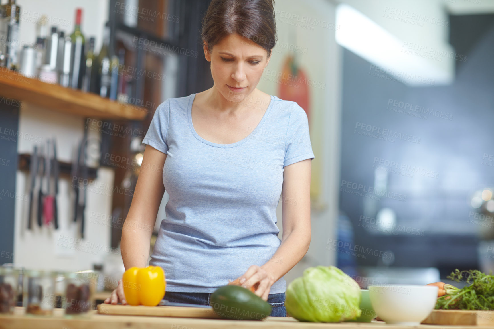 Buy stock photo Shot of an attractive woman chopping vegetables at a kitchen counter