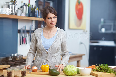 Buy stock photo Shot of an attractive woman standing behind a kitchen counter filled with vegetables