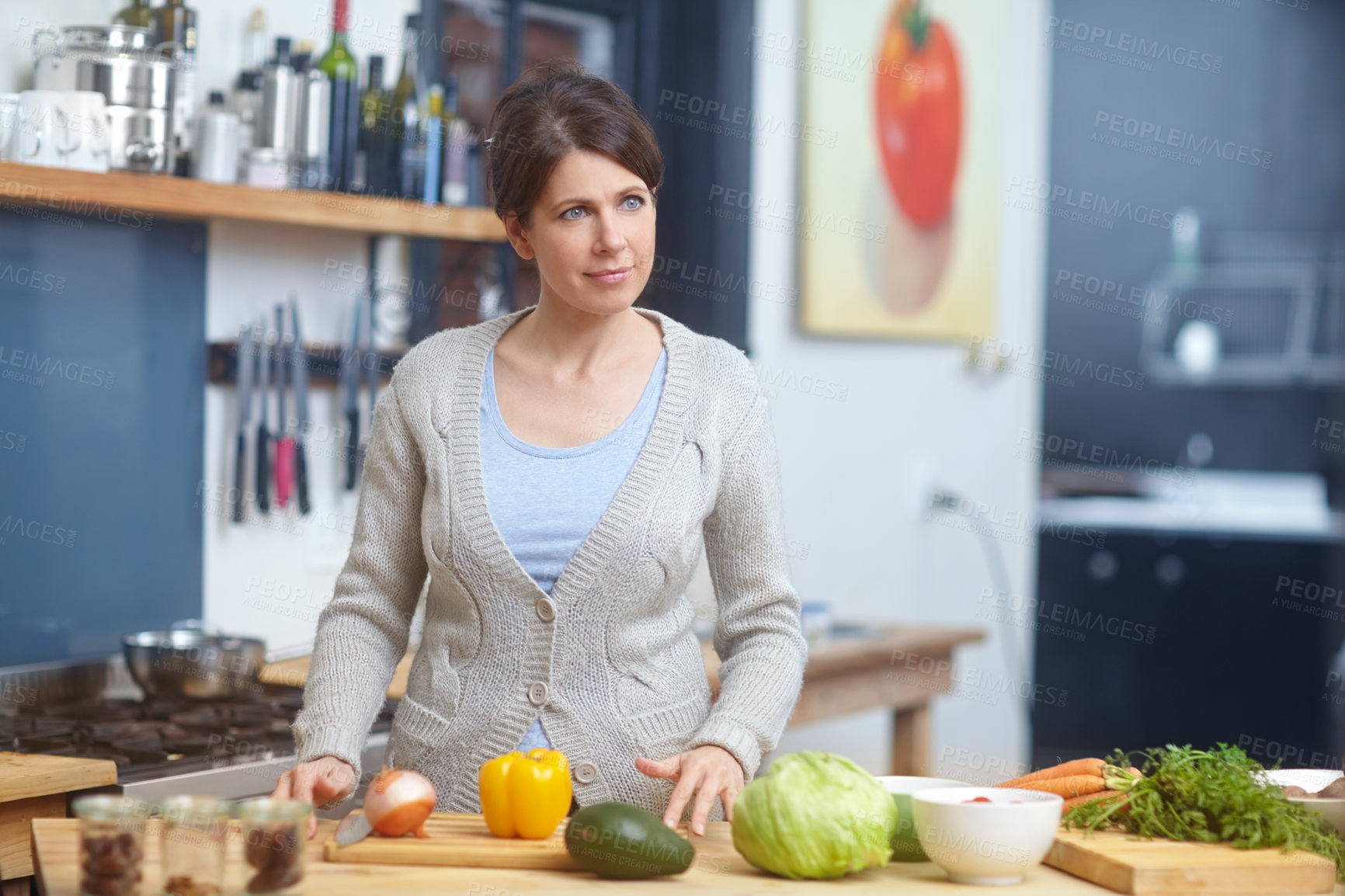 Buy stock photo Shot of an attractive woman standing behind a kitchen counter filled with vegetables