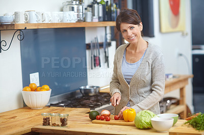 Buy stock photo Shot of an attractive woman chopping vegetables at a kitchen counter