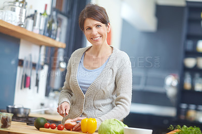 Buy stock photo Shot of an attractive woman chopping vegetables at a kitchen counter