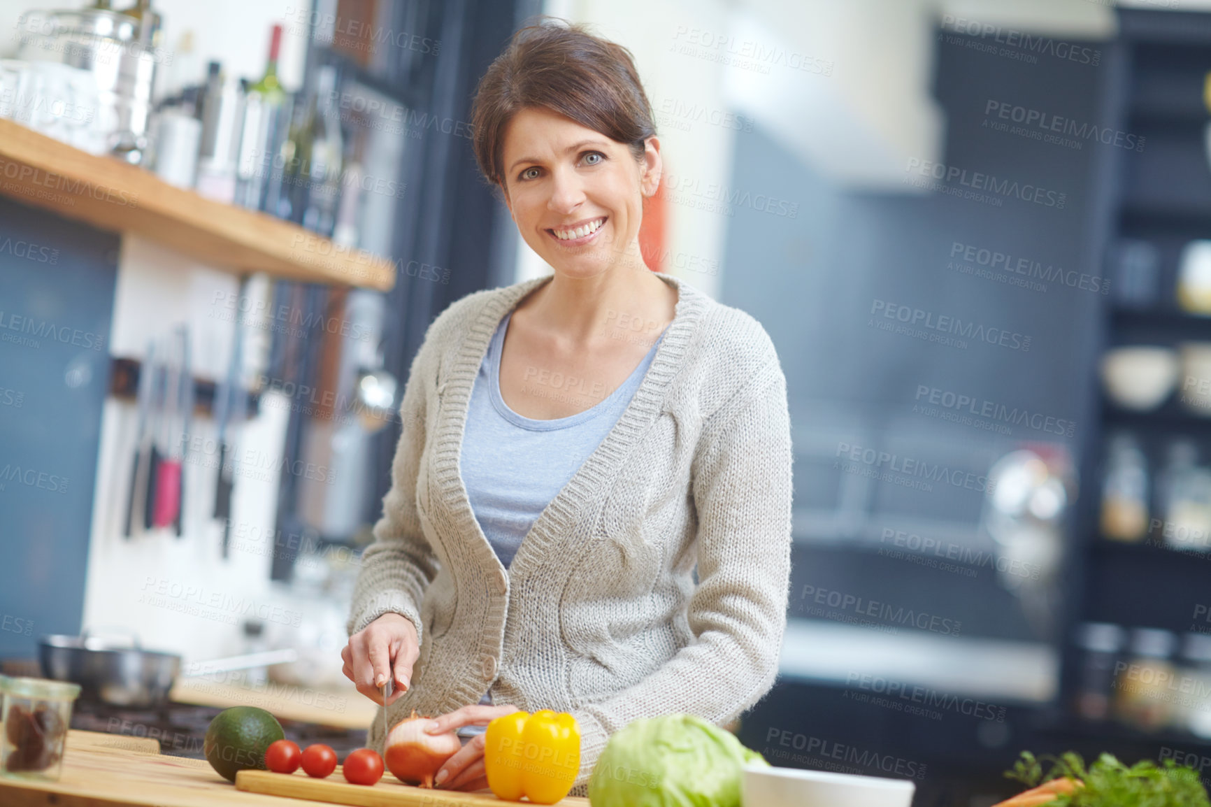 Buy stock photo Shot of an attractive woman chopping vegetables at a kitchen counter