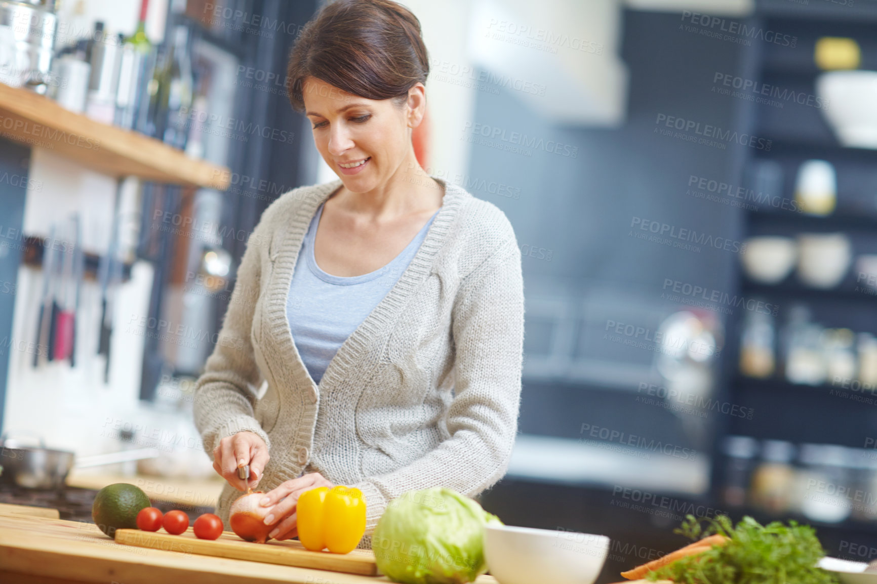 Buy stock photo Shot of an attractive woman chopping vegetables at a kitchen counter