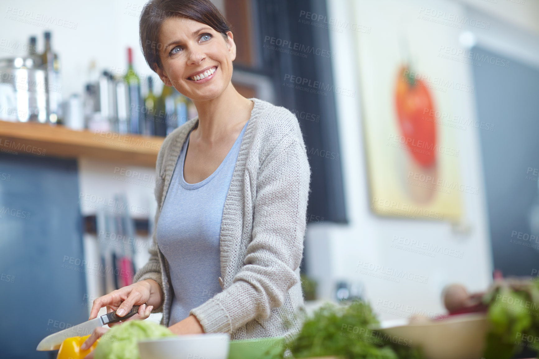 Buy stock photo Shot of an attractive woman looking thoughtful while preparing food in the kitchen