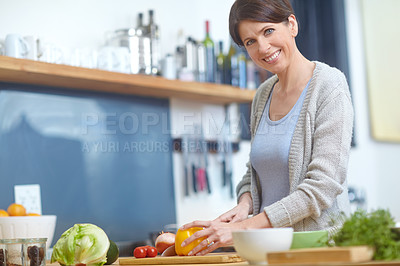 Buy stock photo Portrait of an attractive woman chopping vegetables at a kitchen counter