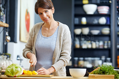 Buy stock photo Shot of an attractive woman chopping vegetables at a kitchen counter