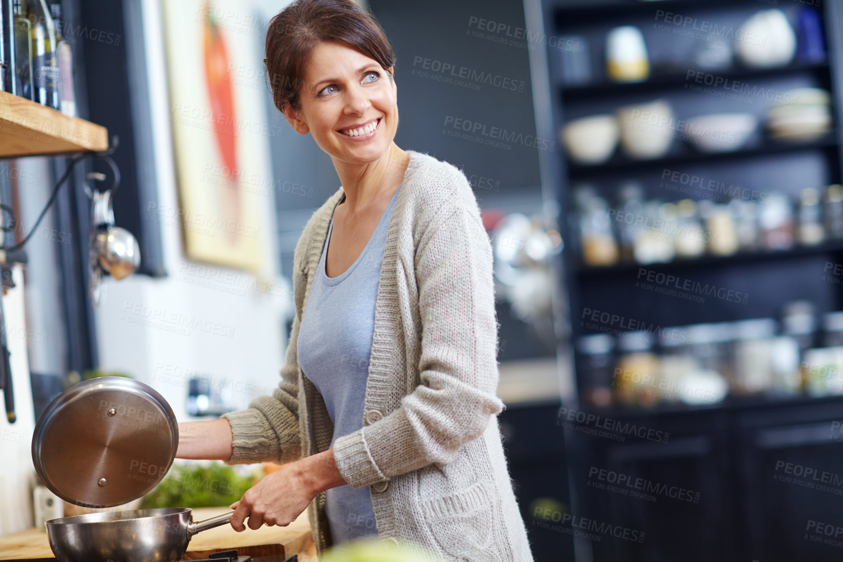 Buy stock photo Shot of an attractive woman looking thoughtful while preparing food in the kitchen