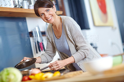 Buy stock photo Shot of an attractive woman preparing food on the kitchen stove