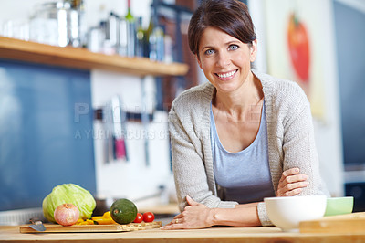 Buy stock photo Portrait of an attractive woman leaning on a kitchen counter filled with vegetables