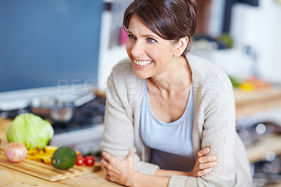 Buy stock photo Shot of an attractive woman leaning on a kitchen counter filled with vegetables