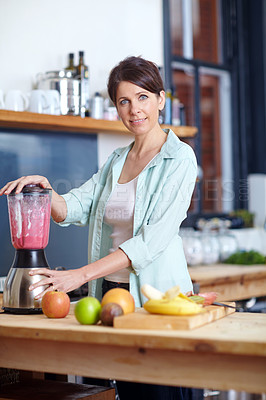 Buy stock photo Shot of an attractive woman making a fruit smoothie in the kitchen