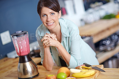 Buy stock photo Portrait of an attractive woman making a fruit smoothie in the kitchen