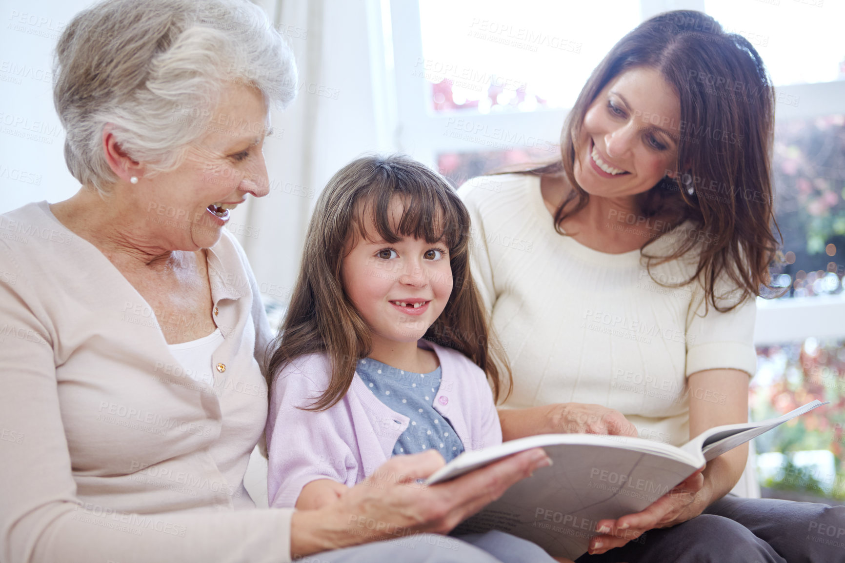 Buy stock photo Reading, portrait and child with mom and grandmother on sofa in living room for bonding together. Happy, relax and girl with mother and senior woman enjoying fantasy story, novel or book at home.