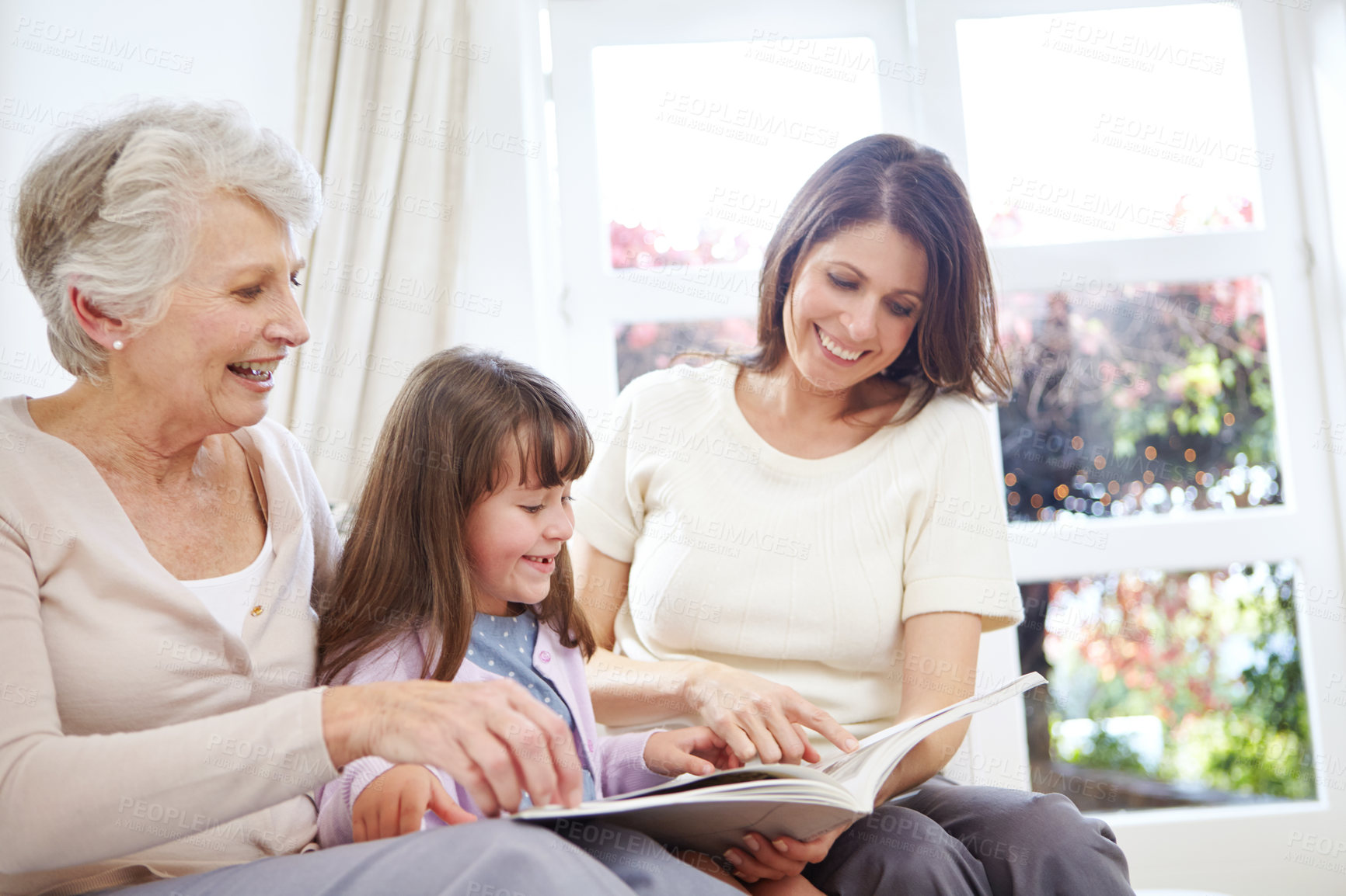 Buy stock photo Reading, novel and child with mom and grandmother on sofa in living room for bonding together. Happy, relax and girl with mother and senior woman enjoying fantasy story, book or literature at home.