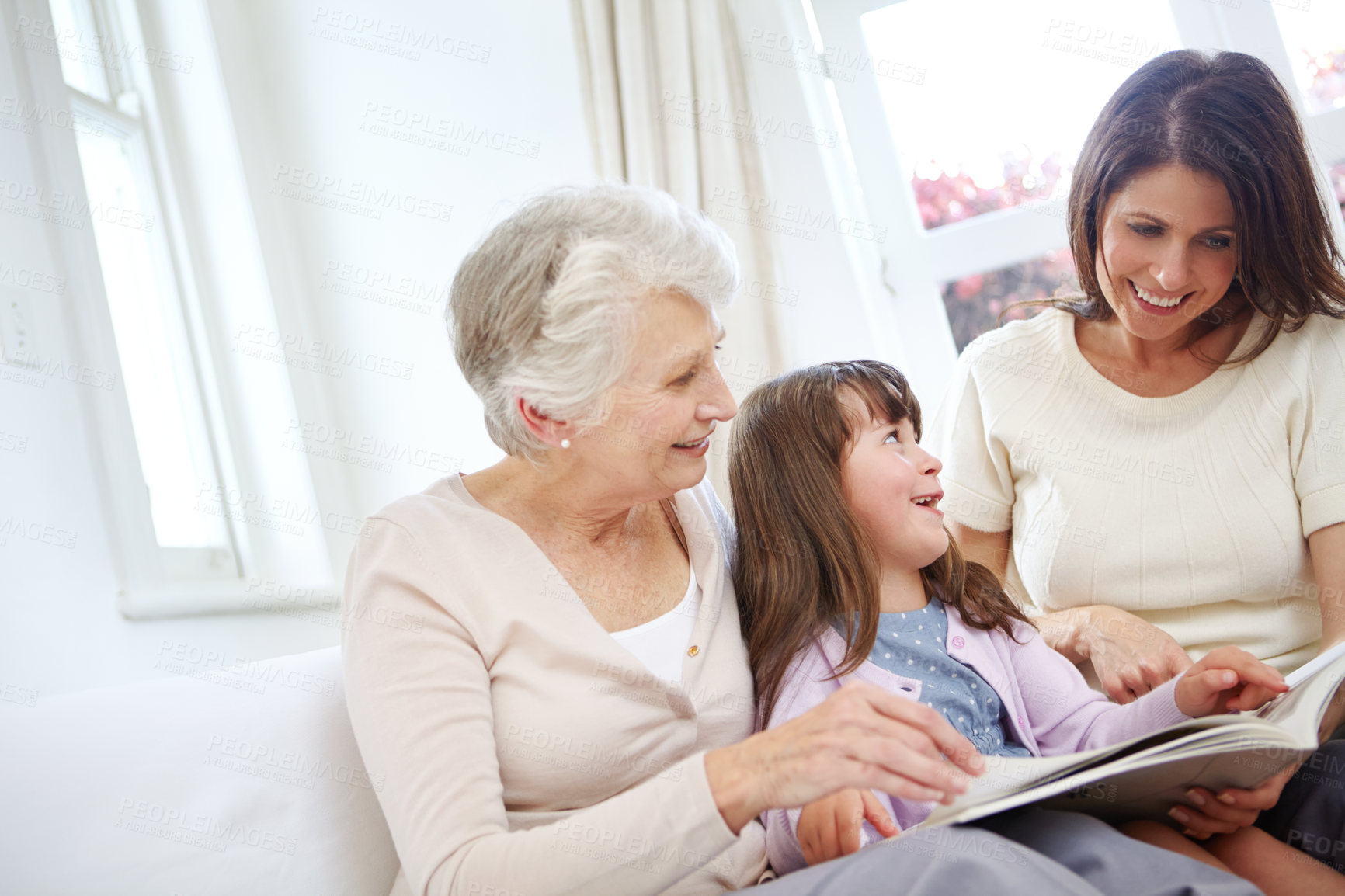 Buy stock photo Reading, book and kid with mom and grandmother on sofa in living room for bonding together. Happy, relax and girl child with mother and senior woman with fantasy story, novel or literature at home.