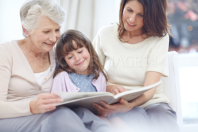 Buy stock photo Shot of a little girl sitting with her mother and grandmother and reading a book
