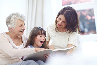 Buy stock photo Shot of a little girl sitting with her mother and grandmother and reading a book
