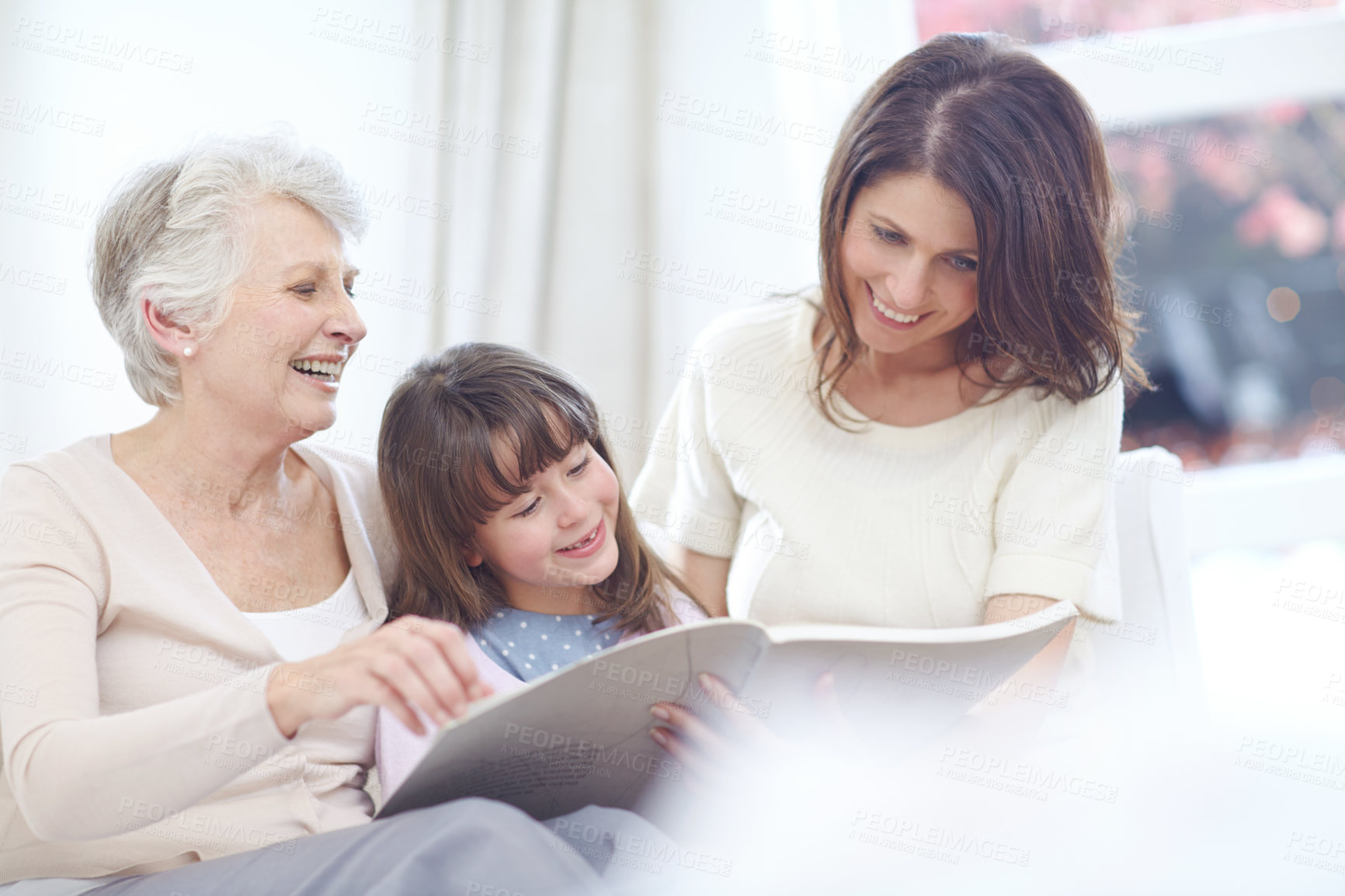 Buy stock photo Reading, laugh and child with mom and grandmother on sofa in living room for bonding together. Happy, relax and girl with mother and senior woman enjoying fantasy story, novel or book at home.