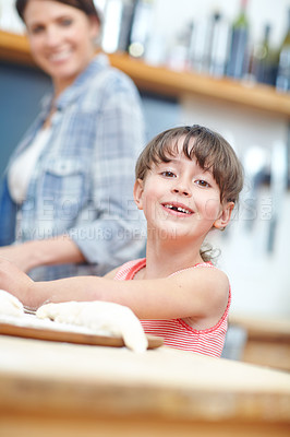 Buy stock photo A cute little girl working with cookie dough with her mother standing in the background