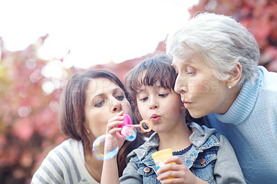 Buy stock photo Shot of a three generational family blowing bubbles together