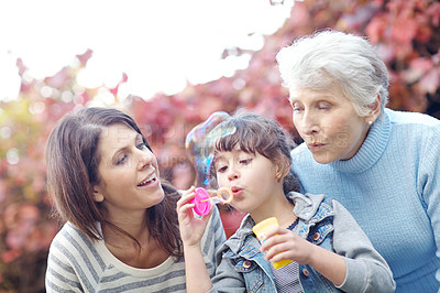Buy stock photo Shot of a three generational family blowing bubbles together