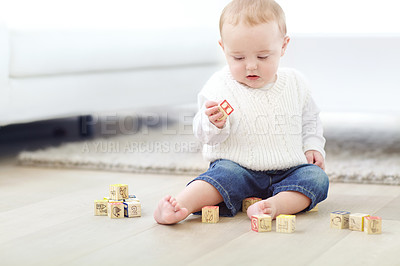 Buy stock photo An adorable little boy wearing casual clothing while playing with his blocks