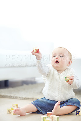 Buy stock photo An adorable little boy wearing casual clothing while playing with his blocks