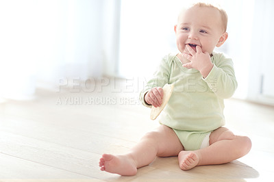 Buy stock photo Shot of a baby boy sitting on the floor while eating a snack