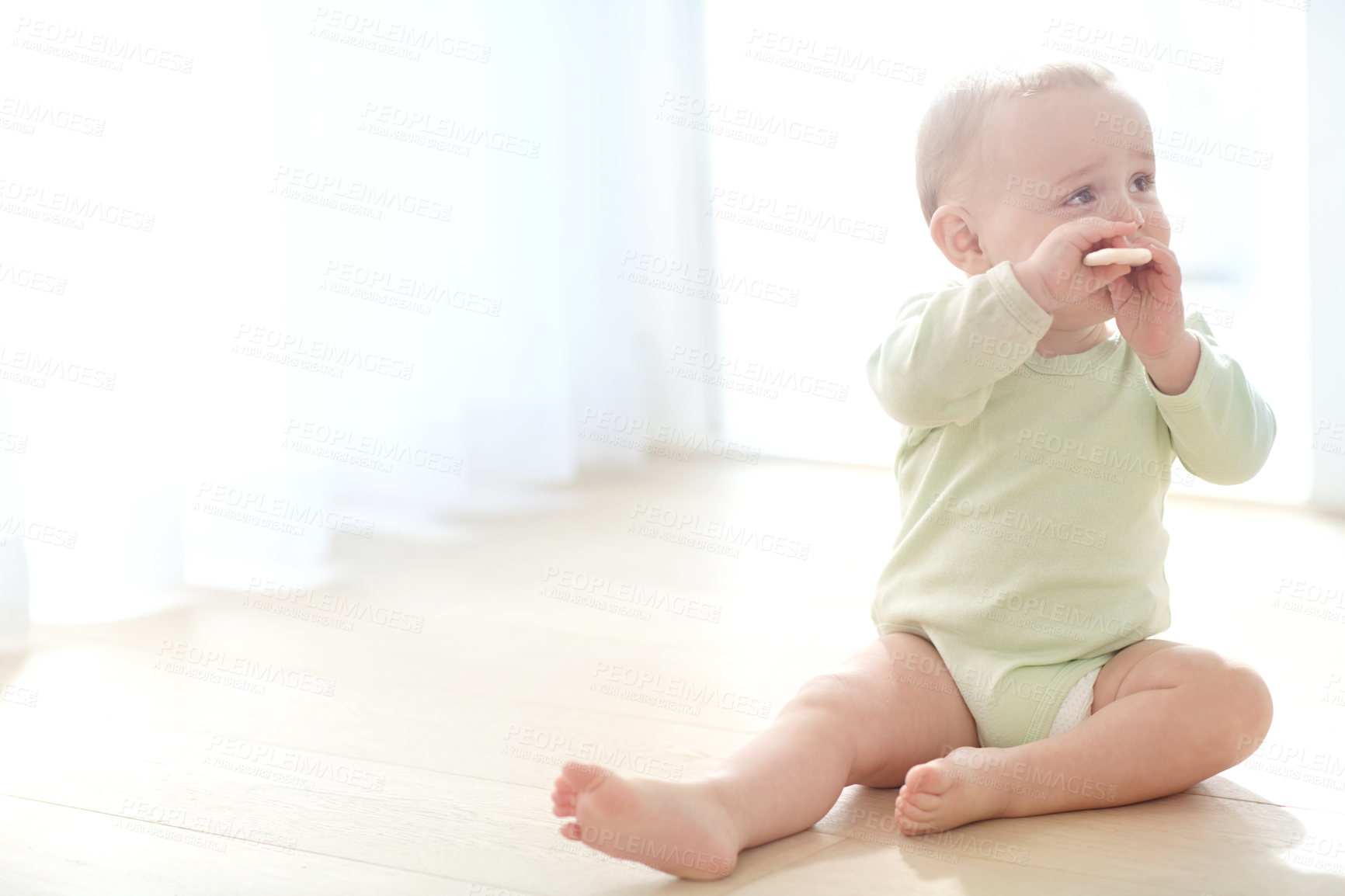 Buy stock photo Shot of a baby boy sitting on the floor while eating a snack