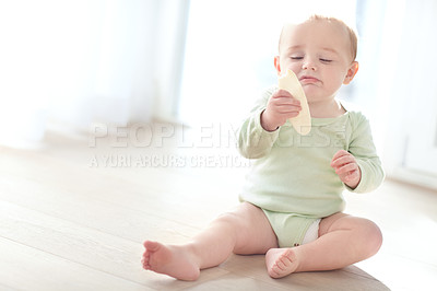 Buy stock photo Shot of a baby boy pulling his face while looking at his snack