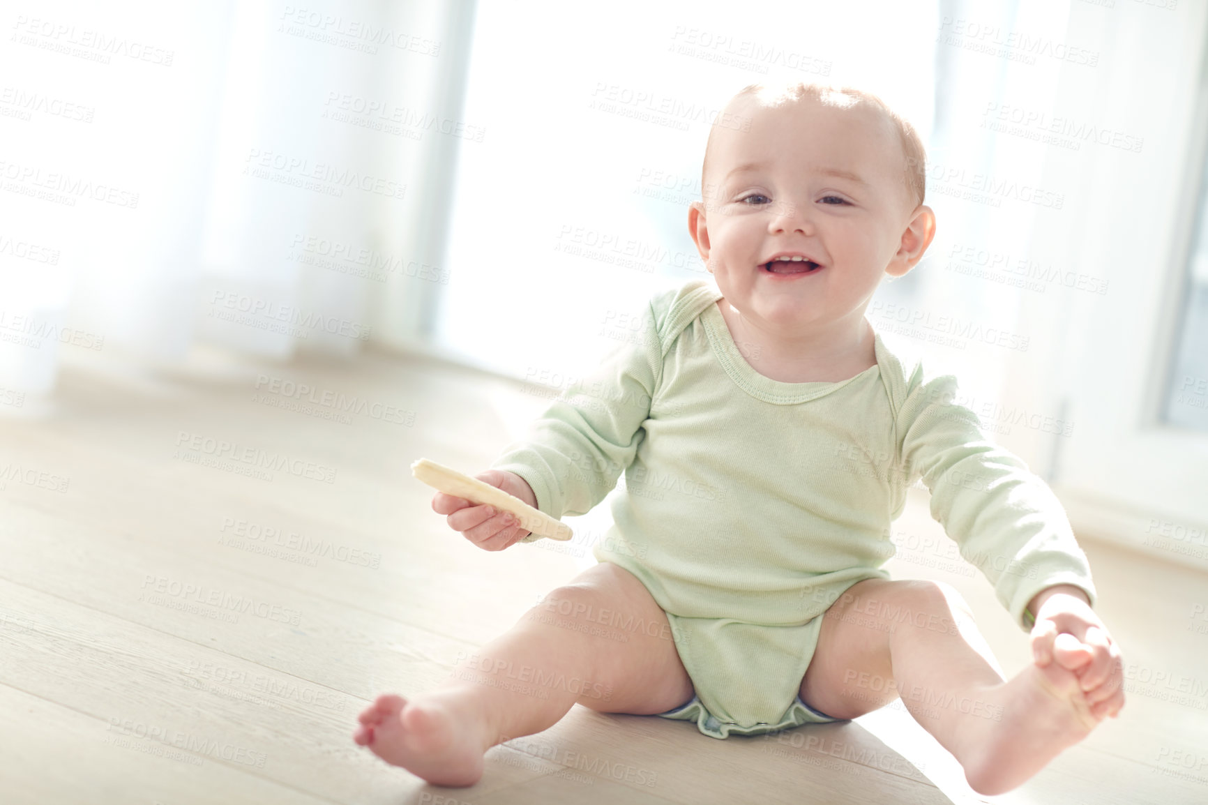 Buy stock photo Shot of a baby boy sitting on the floor while eating a snack