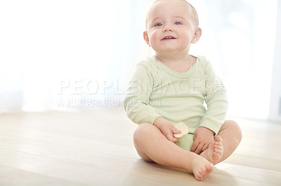 Buy stock photo Shot of a baby boy sitting on the floor while eating a snack