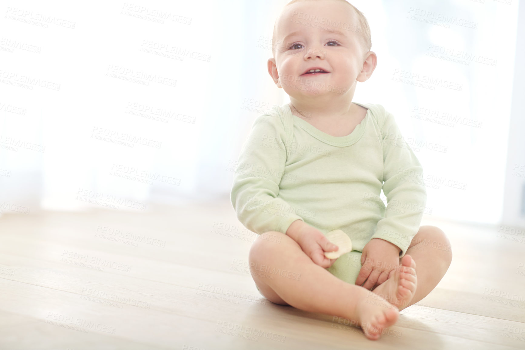 Buy stock photo Shot of a baby boy sitting on the floor while eating a snack