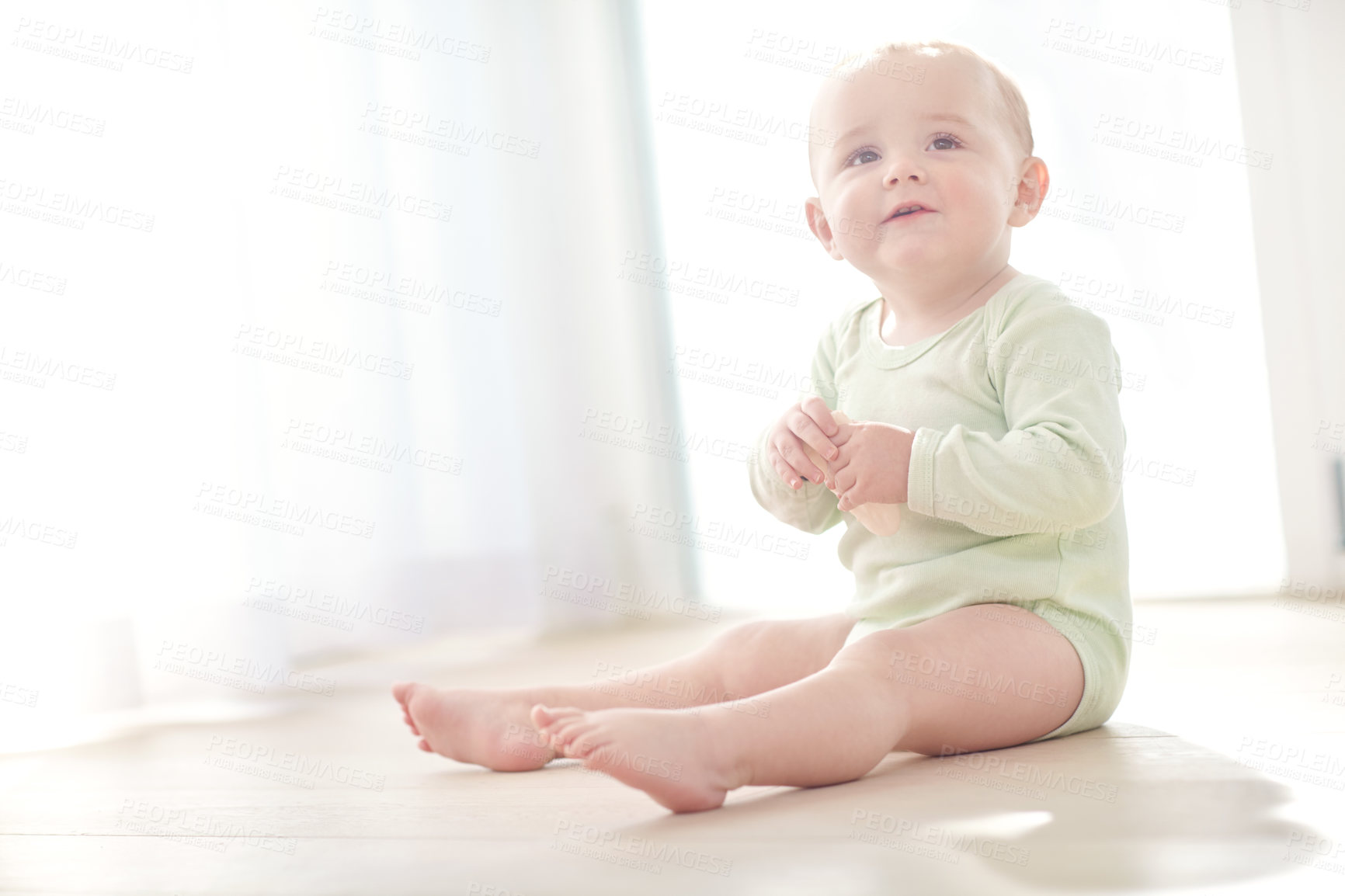 Buy stock photo Shot of a baby boy sitting on the floor while eating a snack