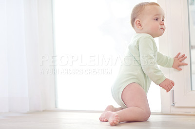 Buy stock photo Shot of a baby boy staring curiously at the window