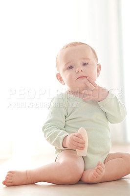 Buy stock photo Portrait of a baby boy sitting on the floor while eating a snack