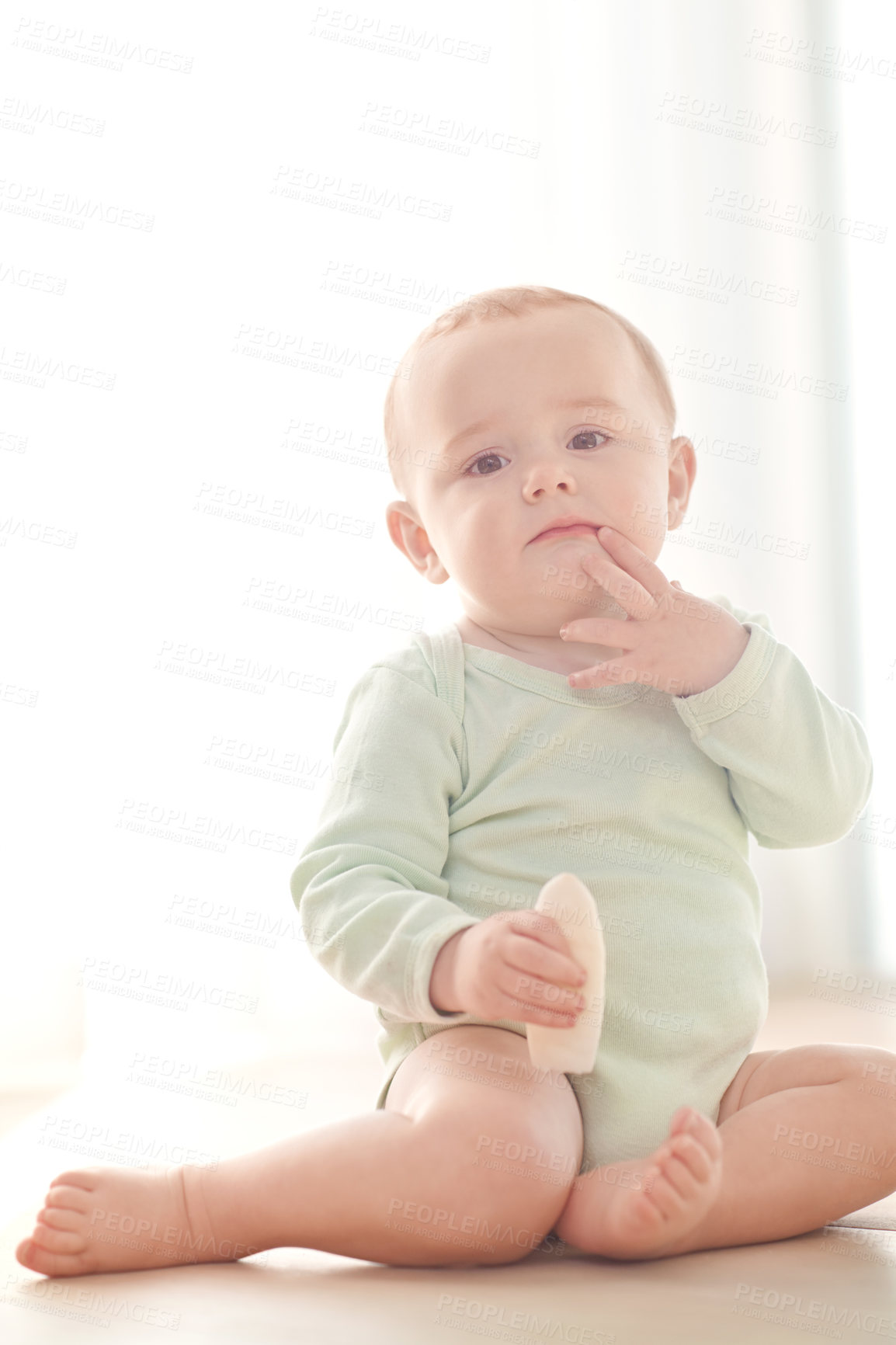 Buy stock photo Portrait of a baby boy sitting on the floor while eating a snack