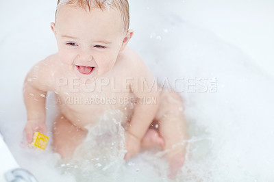 Buy stock photo Shot of an adorable baby boy playing with a toy while bathing