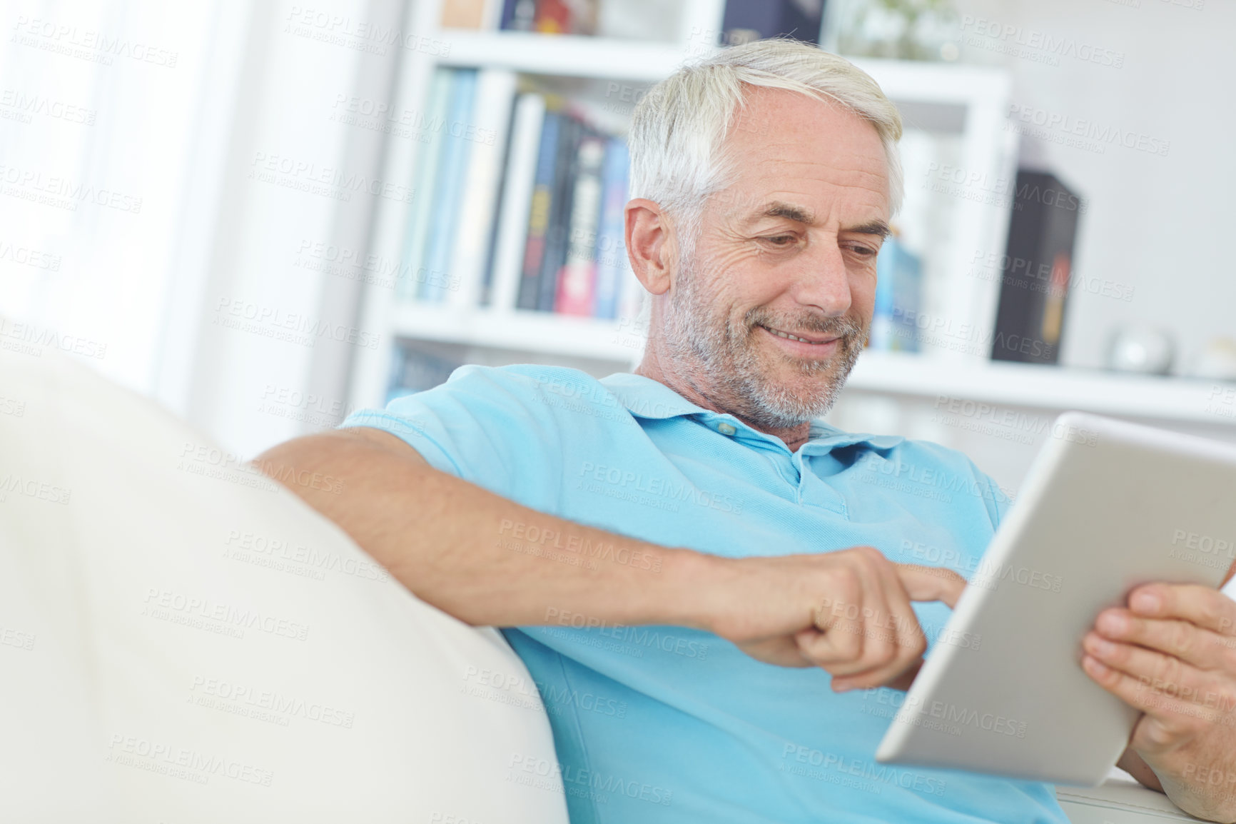 Buy stock photo Mature man, digital tablet or relax on sofa in house, home or apartment living room on social media app or internet game. Smile, happy or retirement person on technology crossword puzzle or streaming