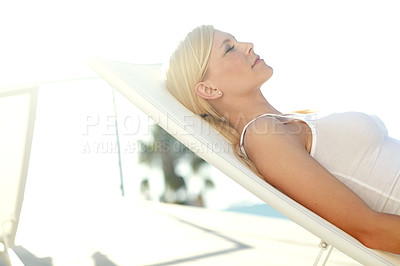 Buy stock photo Shot of a beautiful blonde woman sunbathing on a deck chair