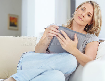 Buy stock photo Shot of an attractive mature woman sitting with a digital tablet at home