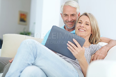 Buy stock photo Mature couple, tablet or relax on sofa in house or home living room on social media or internet app. Happy smile, retirement man or woman on digital technology for video call, movie streaming or news